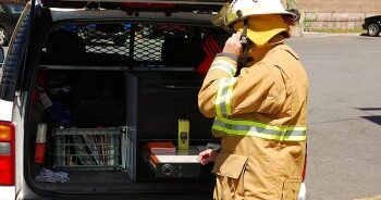Fire person checking an accountability board from the back of an SUV.