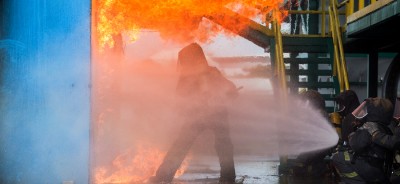 Firemen Using Water From Hose For Fire Fighting At Firefight Tra