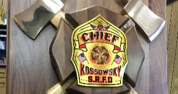 Choosing Custom Firefighter Plaques For Department Recognition 1 A plate with two axes and a golden shield. The place is on a wooden board.