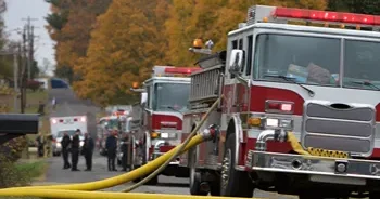 A row of fire trucks and other emergency vehicles on the side of a street.
