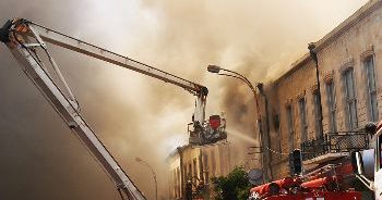 A team of firefighters using a truck lift trying to prevent a building collapse.